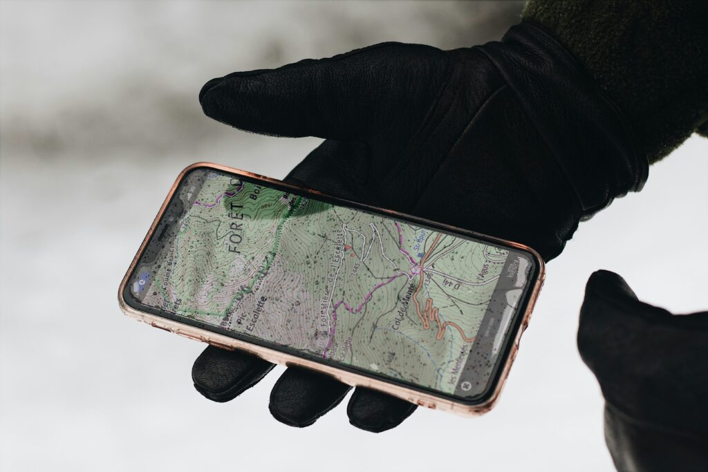 Image of a mobile phone showing maps held by a hand in a black glove.