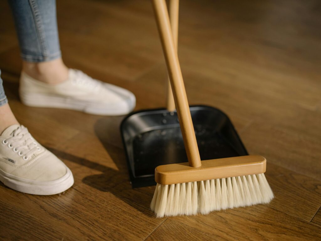 image of someone using dust and brush to remove dust from the floor