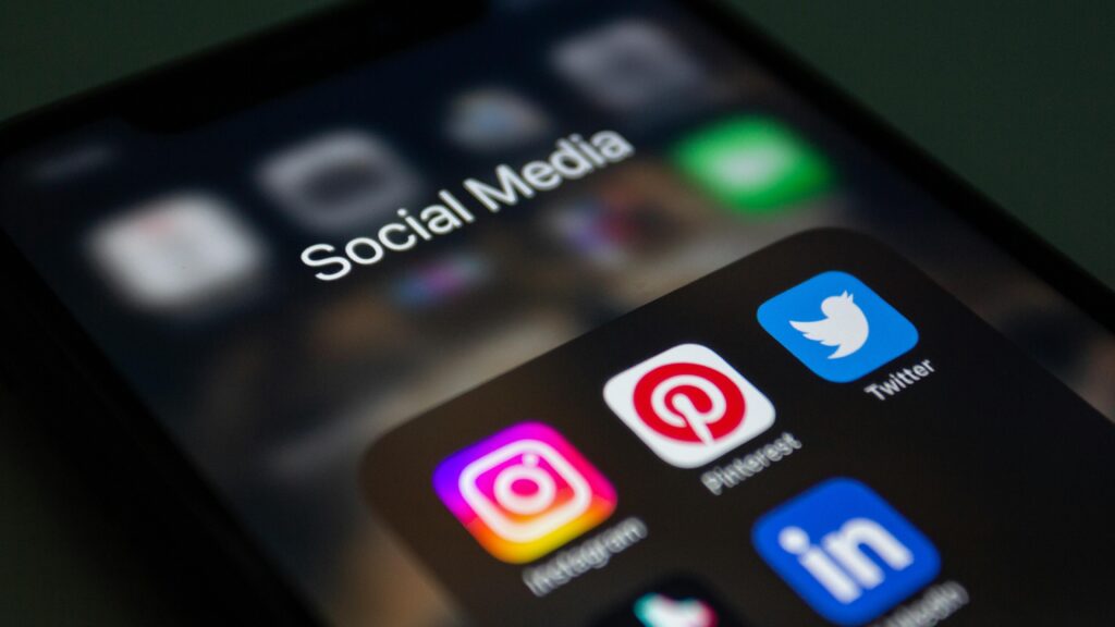 Image of a phone showing icons of major social media platforms like Instagram, Pinterest, Twitter, and LinkedIn